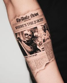 a man's arm with a newspaper tattoo on it that reads, where's the joker?