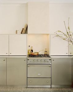 a stove top oven sitting inside of a kitchen next to white cupboards and drawers