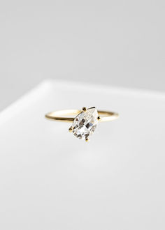 a diamond ring sitting on top of a white surface with the center stone in yellow gold