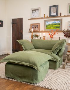 a large green couch sitting on top of a wooden floor next to a white rug