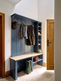 a blue bench with coat racks and boots hanging on the wall next to an open door