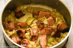 a pot filled with meat and onions on top of a wooden table