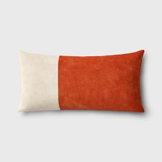 an orange and white pillow on a gray background