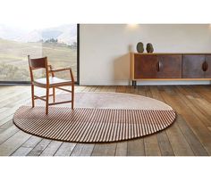 a wooden chair sitting on top of a hard wood floor next to a large window