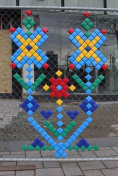 a colorful sculpture made out of legos behind a chain link fence in front of a building