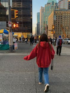 a woman walking down the street in front of tall buildings