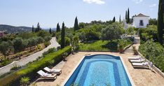 an outdoor swimming pool surrounded by greenery and trees with lounge chairs on the side