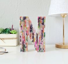 the letter m is made out of magazines and sits next to a pair of glasses