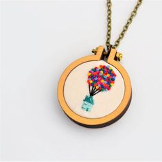 a small embroidered necklace with a hand holding a bunch of beads on it's back