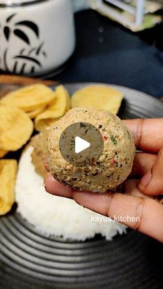 a person is holding a cracker in front of some food on a plate with chips