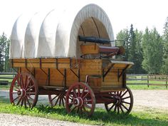 an old covered wagon is parked on the grass