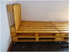 a bed made out of wooden pallets in a room with tile flooring and white walls