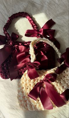 two baskets with red bows on them sitting on a white cloth covered tablecloth, next to each other