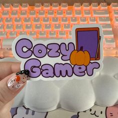 someone holding up a sticker that says cozy gamer