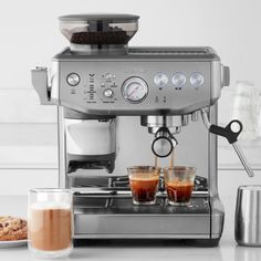 an espresso machine with two cups of coffee next to it