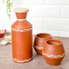 three clay pots and one vase sitting on a table