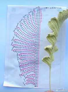 a crocheted flower is shown in front of a piece of paper that has been made into a pattern