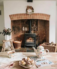 a table with tea cups and pastries on it in front of a fire place