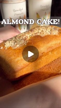 someone holding a loaf of bread with almonds on top and the words almond cake above it