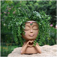 a clay sculpture of a woman's face with leaves on her head