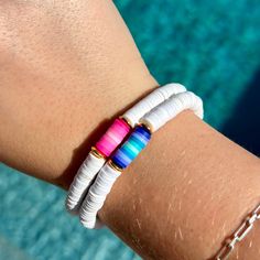 a close up of a person's arm wearing a bracelet with multicolored beads