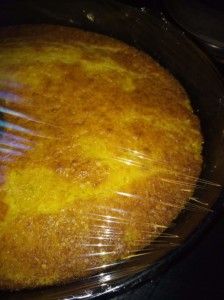 a yellow cake in a pan with plastic wrap around it's edges and on top of the stove