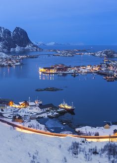 an aerial view of a town in the middle of a body of water with mountains in the background