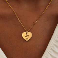 a woman wearing a gold necklace with a heart shaped pendant on it's neck