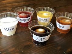 several cups filled with different types of drinks on top of a wooden table next to each other