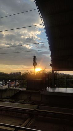 the sun is setting behind some power lines and wires above train tracks in an urban area