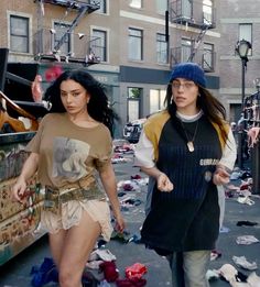 two women walking down the street with trash all over them