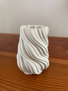 a white vase sitting on top of a wooden table