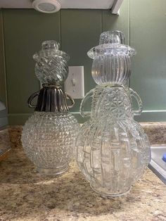 two clear glass vases sitting on top of a counter next to a faucet