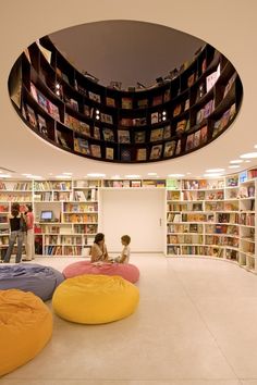 two children sitting on bean bags in the middle of a room with bookshelves