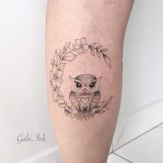 an owl tattoo on the leg with flowers around it