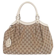 Authentic, pre-loved Gucci Sukey GG monogram canvas top handle bag. The Sukey top handle bag keeps all your necessities in check. Features beige/ebony original Gucci canvas with beige leather trim, light gold hardware, detachable interlocking GG leather tag, double rolled handles, snap closure, reinforced leather corners, snap sides, large interior with zipper pockets. Add your book, iPad, phone, cosmetic case, wallet, keys, and more. You're going to love this bag. Authenticity model code: 21194 Louis Vuitton Crossbody Bag, Louis Vuitton Crossbody, Weekend Travel Bags, Mario Testino, Louis Vuitton Vernis, Gg Monogram, Leather Tag, Cute Nike Shoes, Cute Nikes