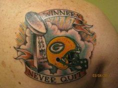 a green bay packers tattoo on the back of a man's shoulder with an inscription that reads winners never quit