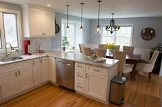 a large kitchen with white cabinets and wooden floors is pictured in this image, there are many chairs around the island