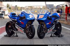 two blue motorcycles are parked on the track