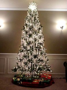 a white christmas tree with lights and presents on the bottom is shown in an instagram post