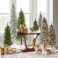 christmas trees and presents on a table in front of a window