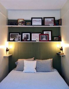 there is a bed with pictures on the wall above it and two lamps at the headboard