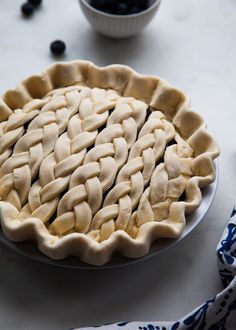 an uncooked pie sitting on top of a table next to bowls of blueberries