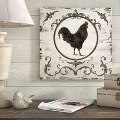 a rooster is on the wall next to some books and a lamp in a room