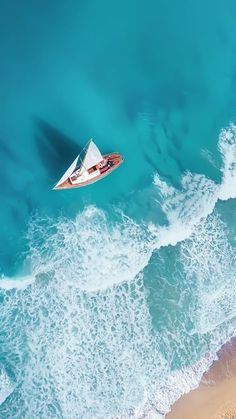 an aerial view of a boat in the ocean with blue water and white foamy waves