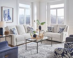 a living room with couches, chairs and tables in front of two large windows