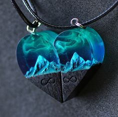 two heart shaped pendants with mountains in the background on a black leather cord necklace