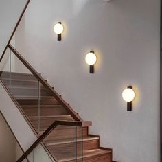 three lights that are on the side of a stair case next to a banister