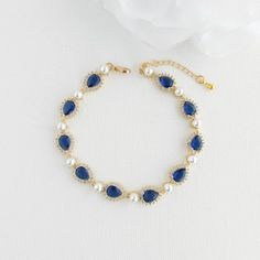 Timeless Blue Wedding Bracelet with Pearls in Gold: To Embrace Your "Something Blue" Wedding Day Tradition With this beautiful blue wedding bracelet with pearls and gold, embrace timeless elegance and fulfill the cherished tradition of "something blue" on your wedding day. This exquisite blue bridal bracelet features a classic design, where teardrops of vibrant sapphire blue cubic zirconia alternated with glowing round white pearls and plated in 14k gold. This blue bracelet is versatile whether you're attending a cocktail party, or a formal evening dinner, or want to add a touch of elegance to your everyday wear, this piece is sure to become a cherished part of your jewelry collection. This sapphire blue bracelet also makes a thoughtful and meaningful gift for your daughter, niece, friend, Blue Pearl Bracelet, Blue And White Earrings, Bracelet With Pearls, Blue Bride, Gold Pearl Bracelet, Formal Evening Wear, Something Blue Wedding, Blue Bridal, Gold Bracelet For Women