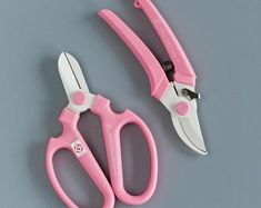 two pairs of pink scissors on a gray surface